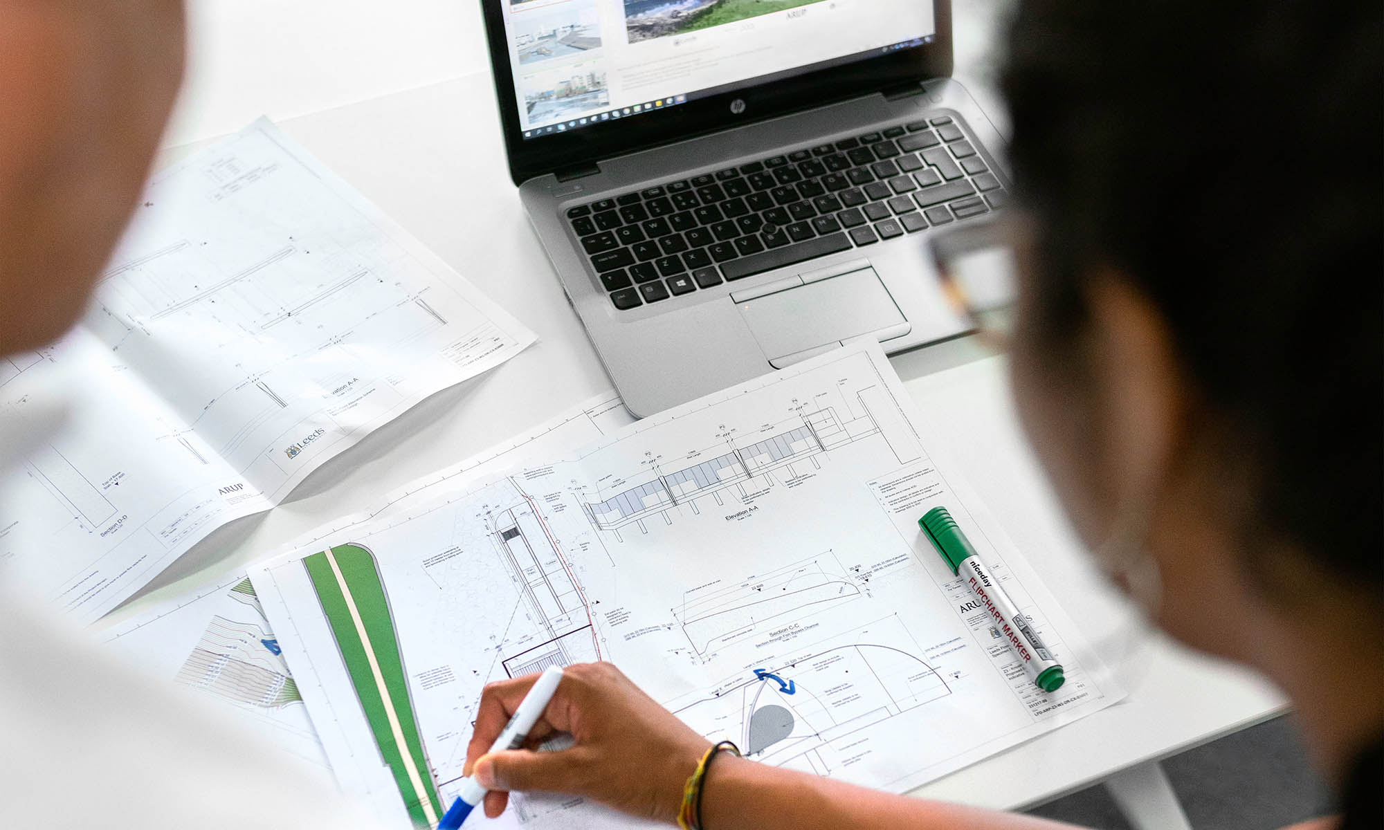 pexels stock photo of two engineers working together over drawings and a laptop